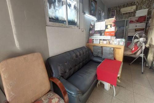 a room with a leather couch and a red stool at Sukhum Mega Bangna Guest House in Ban Khlong Thewa