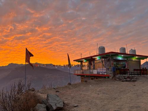 a building on the top of a mountain at sunset at Bijali mahadev valley view home stay in Jari