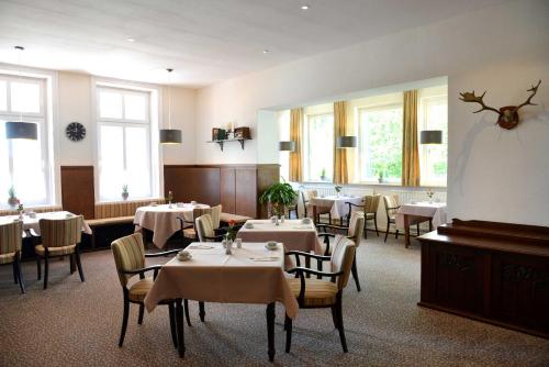 - une salle à manger avec des tables, des chaises et des fenêtres dans l'établissement Arnimsruh Hotel garni, à Lübeck