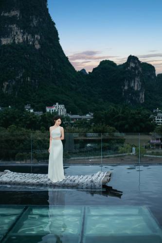 a woman standing on the edge of a body of water at Yangshuo Hidden Dragon Villa in Yangshuo
