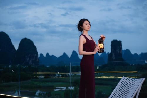 a woman is holding a lamp in her hand at Yangshuo Hidden Dragon Villa in Yangshuo