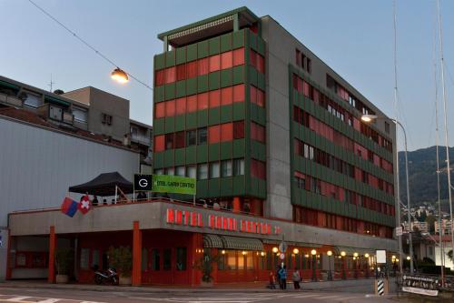 a green and red building with people in front of it at Hotel Garni Centro in Chiasso