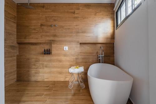 a bathroom with a white tub and a wooden wall at Pé Na Areia, 6 Quartos, Casa Azul in Bertioga