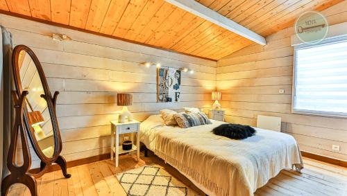 ein Schlafzimmer mit einem Bett in einem Zimmer mit Holzwänden in der Unterkunft Villa Ocean in Les Bussolleries