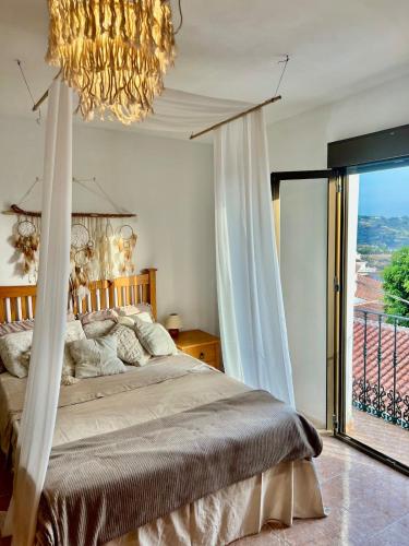 a bedroom with a bed with a chandelier and a window at Sunshine Home Competa in Cómpeta
