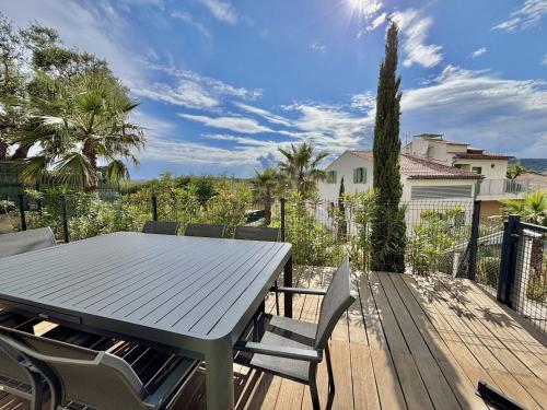 une terrasse en bois avec une table et des chaises dessus dans l'établissement Angeline, à Sainte-Maxime
