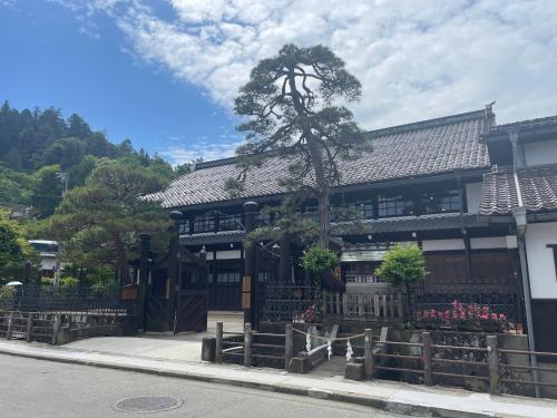 a building with a tree in front of it at HOTEL AMANEK HidaTakayama in Takayama