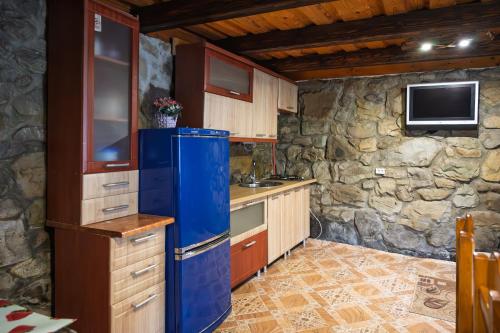 a kitchen with a blue refrigerator and a stone wall at Котеджі "У Яни" in Yablunytsya