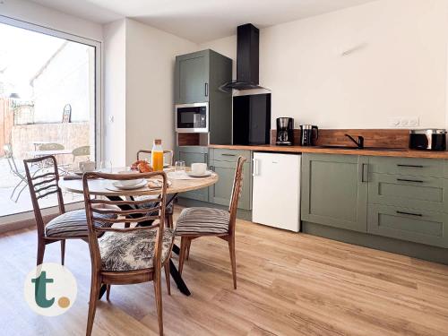 une cuisine avec une table et des chaises dans une cuisine dans l'établissement Tranquiloue - Appart Centre-Ville - Puy du Fou 20min, aux Herbiers