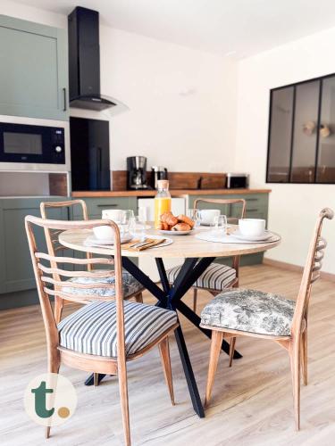 une table et des chaises dans une cuisine avec une table et des chaises dans l'établissement Tranquiloue - Appart Centre-Ville - Puy du Fou 20min, aux Herbiers