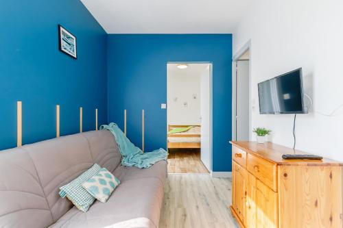 un salon avec un canapé et un mur bleu dans l'établissement 05 - Le Cygne - Village vacances, à Maché