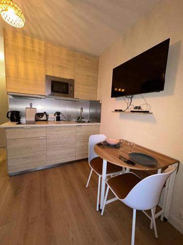 - une cuisine avec une table en bois et des chaises blanches dans l'établissement Studio rénové à 100 mètres de la plage, à Antibes