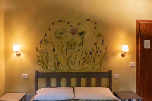 a painting of flowers on a wall above a bed at Eremo Montemezzano in Pratovecchio