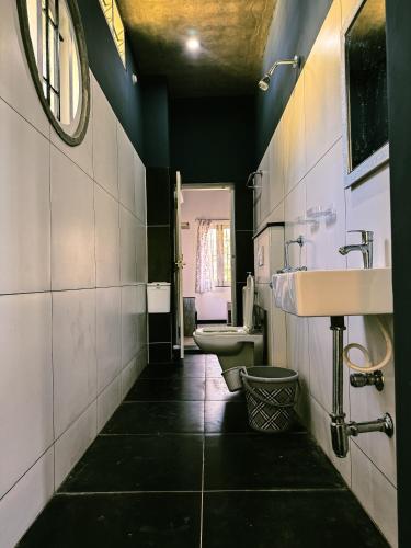 a bathroom with two toilets and a sink and a mirror at Brick and Bare Homestay in Auroville