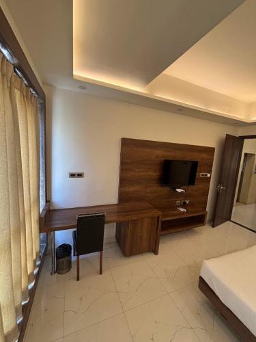 Una habitación con un escritorio con televisión y una cama. en Hotel Ada Regency, en Bhopal