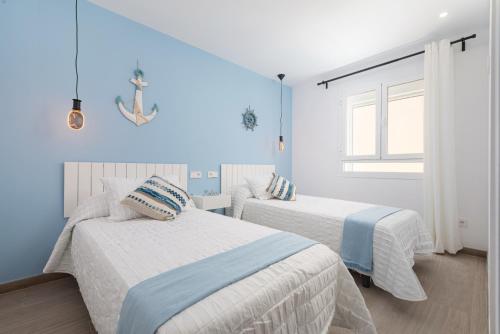 Dos camas en una habitación con paredes azules. en Canyamel A, en Canyamel