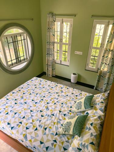 a large bed in a bedroom with two windows at Brick and Bare Homestay in Auroville