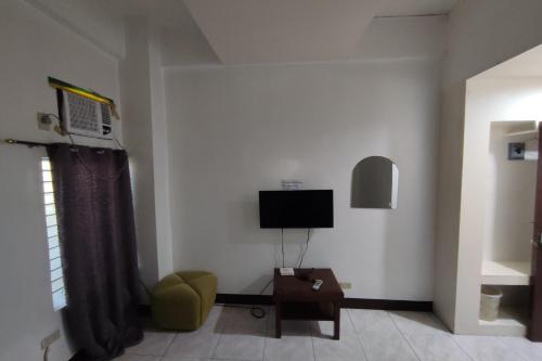 a living room with a television and a chair at Green Ridge Apartelle in Tigbawan