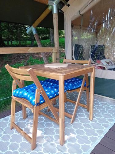 - une table en bois et 2 chaises sur la terrasse dans l'établissement Domaine de Marchal - Le balcon du Parc - tente éco-lodge, à Celles-sur-Durolle