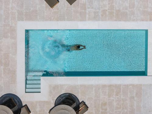 a person is swimming in a swimming pool at Elounda Black Pearl Villa in Agios Nikolaos