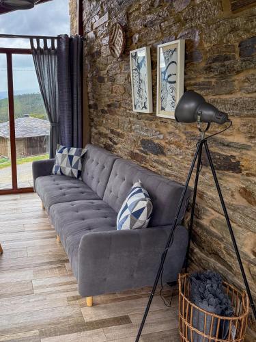 a couch in a living room with a brick wall at Complejo Rural Lar de Vies in A Pontenova