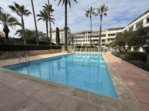 une grande piscine avec des palmiers et un bâtiment dans l'établissement Cannes - 3 pieces a 15mn Palais, à Cannes