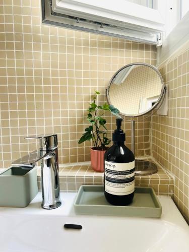 une bouteille de savon posée sur un lavabo à côté d'un miroir dans l'établissement Welcome to Montmartre, à Paris