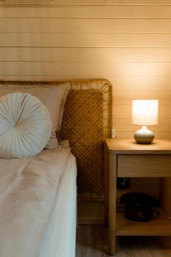 a bed with a table with a lamp and a pillow at Tiny House Sage - ElysianFields in Sadu