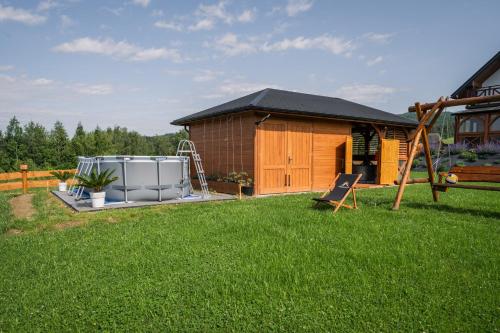 a backyard with a house and a playground at Gorczańska Sapałówka in Maniowy