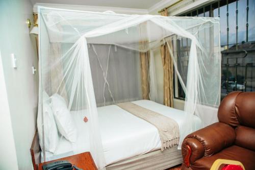 a bedroom with a canopy bed and a chair at MBEYA PARADISE INN in Mbeya