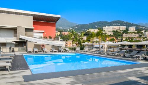 - une piscine en face d'un bâtiment avec des chaises dans l'établissement Résidence Pierre & Vacances Premium Julia Augusta, à Roquebrune-Cap-Martin
