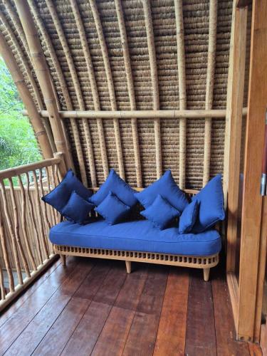 a bench with blue pillows sitting on a porch at Tricky Trees Lodges in Gili Air
