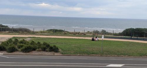 two people sitting on the grass near the ocean at Sunset Guest Suite in Aldinga Beach