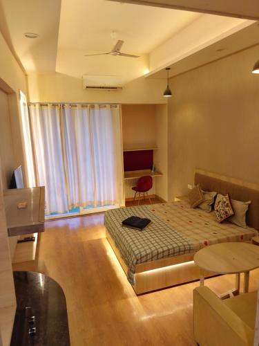 a bedroom with a bed and a chair and a table at Gaur City Mall Homestay in Ghaziabad
