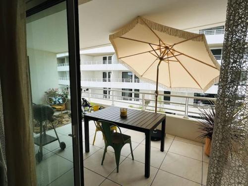 une table avec un parasol sur un balcon dans l'établissement Valras-Loc Archipel Panarea Terrasse et Vue Mer, à Valras-Plage