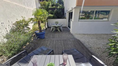 un patio avec une table, des chaises et un palmier dans l'établissement Saint Georges de Didonne - CONFORT et DETENTE pour cet APPARTEMENT - 400m PLAGE, à Saint-Georges-de-Didonne