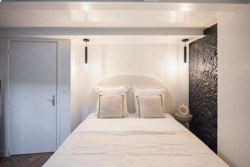 une chambre avec un lit avec des draps blancs et des oreillers dans l'établissement Modern apartment in Nation, à Paris