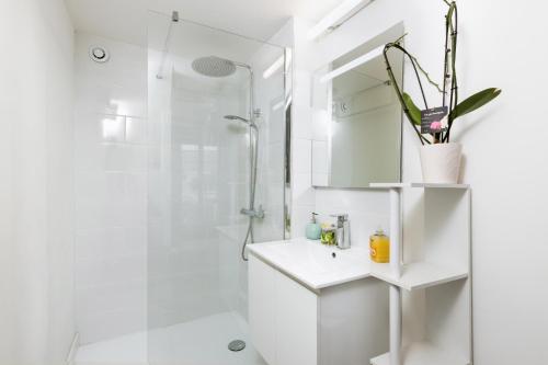 une salle de bain blanche avec une douche et un lavabo dans l'établissement La Maison du Plaisir, à Gruissan