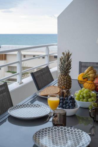 une table avec des assiettes de nourriture et des fruits sur un balcon dans l'établissement Valras-Loc Archipel Panarea Vue Mer et Confort, à Valras-Plage