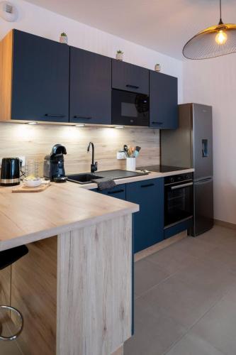 une cuisine avec des armoires bleues et un comptoir dans l'établissement Valras-Loc Archipel Panarea Vue Mer et Confort, à Valras-Plage