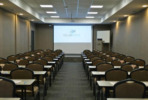 a lecture hall with tables and chairs and a screen at Uçar Royal Hotel ve Konferans Salonu in Sile