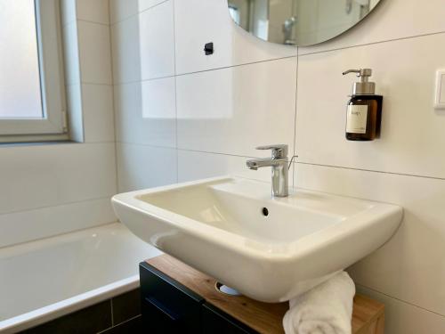 a white bathroom with a sink and a bath tub at MAIN Cozy Casa Peterplatz in Würzburg