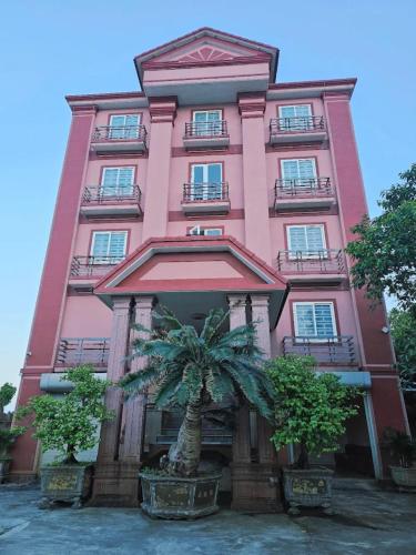 a pink building with a palm tree in front of it at Hoài Thu 2 Hotel in Xã Thanh Trạch