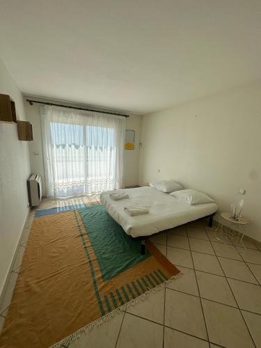 une chambre avec un lit et une grande fenêtre dans l'établissement Appartement vue mer avec garage, à Aytré