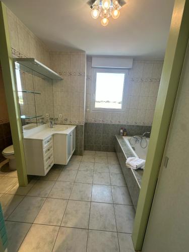 une salle de bain avec une baignoire et un lavabo et une baignoire dans l'établissement Appartement vue mer avec garage, à Aytré