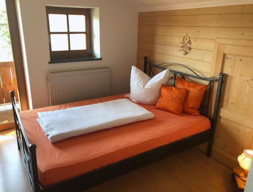 - une chambre avec un lit doté de draps et d'oreillers orange dans l'établissement Bergromantik Apartments Fritzenlehen, à Berchtesgaden