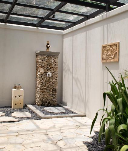 a stone fireplace in a patio with a roof at Plataran Menjangan Resort and Spa - CHSE Certified in Banyuwedang
