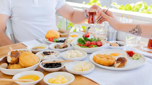 einen Tisch mit Vorspeisen und Schüsseln mit Speisen in der Unterkunft Cunda Piano Otel in Ayvalık