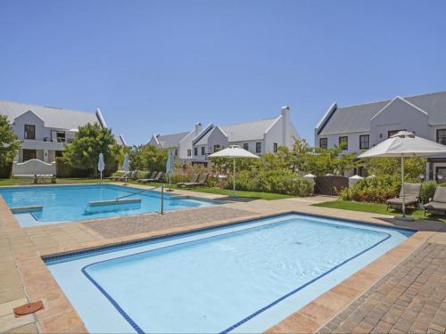 a large swimming pool in a yard with houses at Winelands Golf Lodges 33 in Stellenbosch