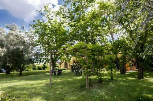 a park with trees and picnic tables in the grass at Rosaspina - Appartamento 6 in Capalbio